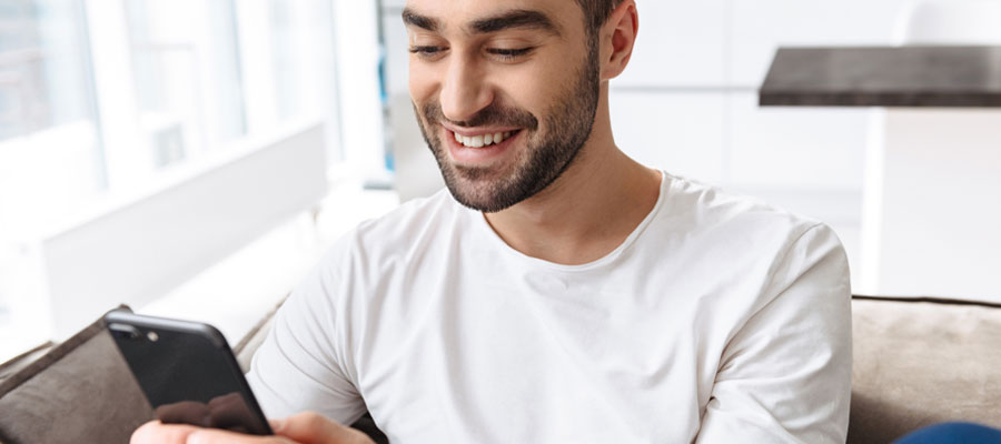 jeune qui sourit devant smartphone